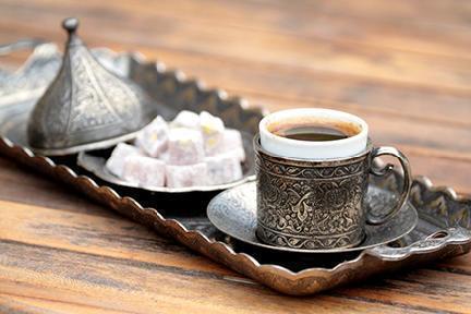 Café y delicias turcas servidas en bandeja y tazas tradicionales en metal repujado