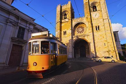 Típico tranvía amarillo transitando frente la Se en Lisboa