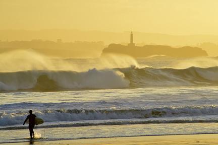 Surfista entrando en un mar crespado frente a Santander