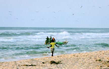 Chica esperando a los pescadores cerca del puerto de Mbour, Senegal