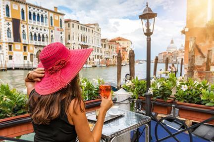 Turista disfrutando de un reflescante spritz al atardecer junto al Gran Canal de Venecia